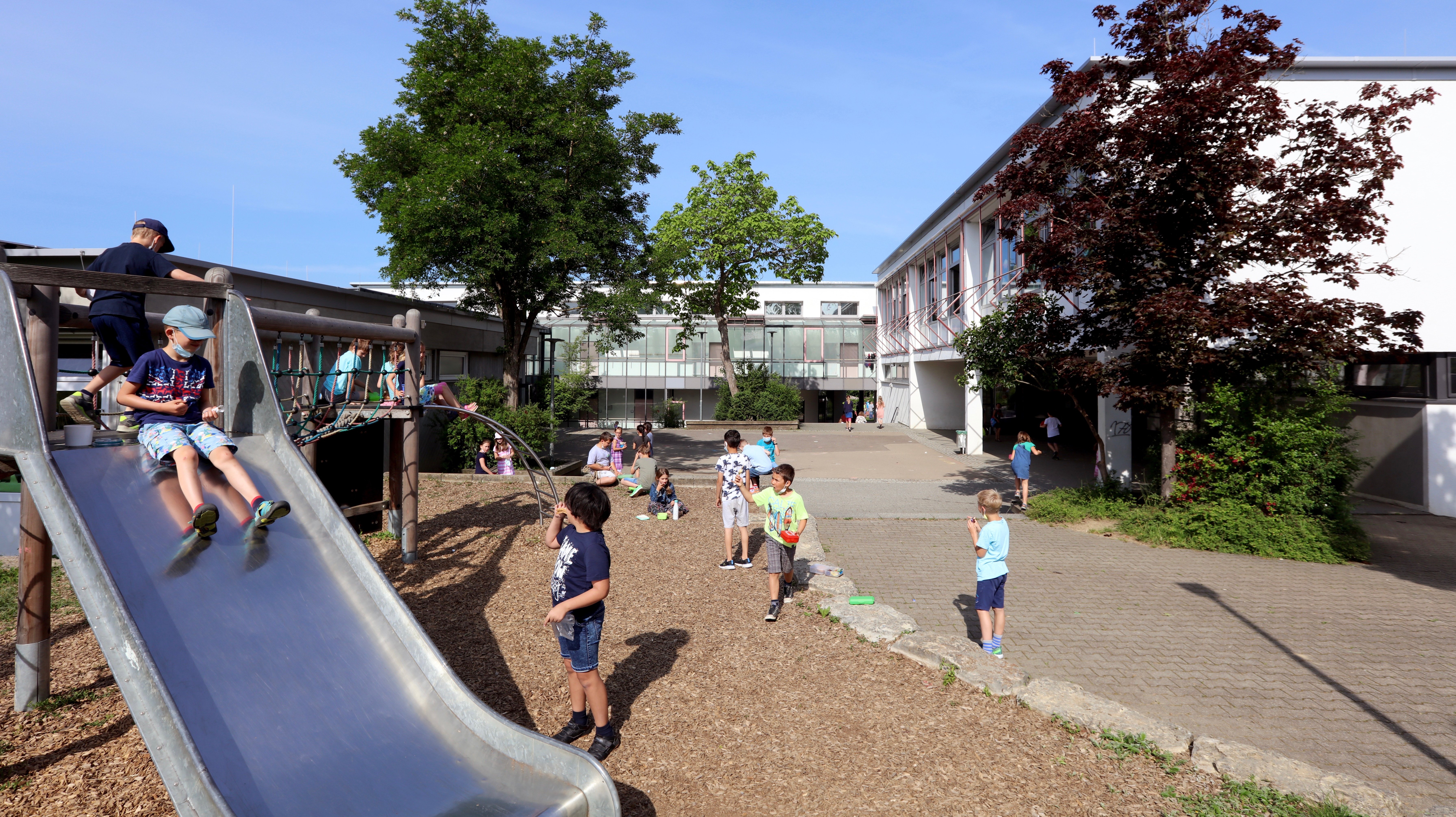 Kinder spielen auf Rutsche auf dem Schulhof 